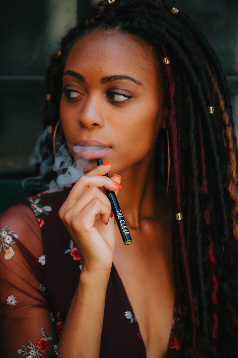 African woman puffing a CBD vape pen