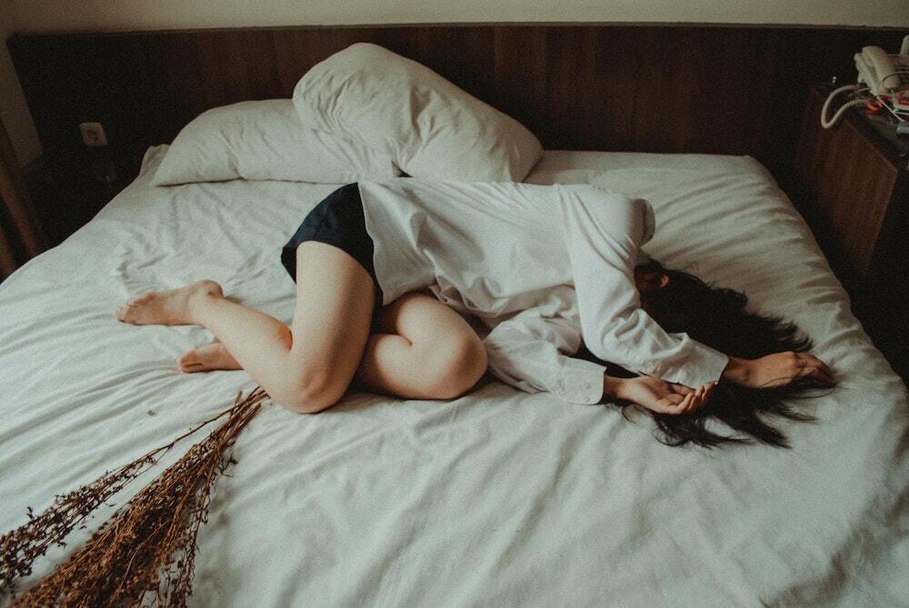 CBD for PTSD girl lying on bed covering her face